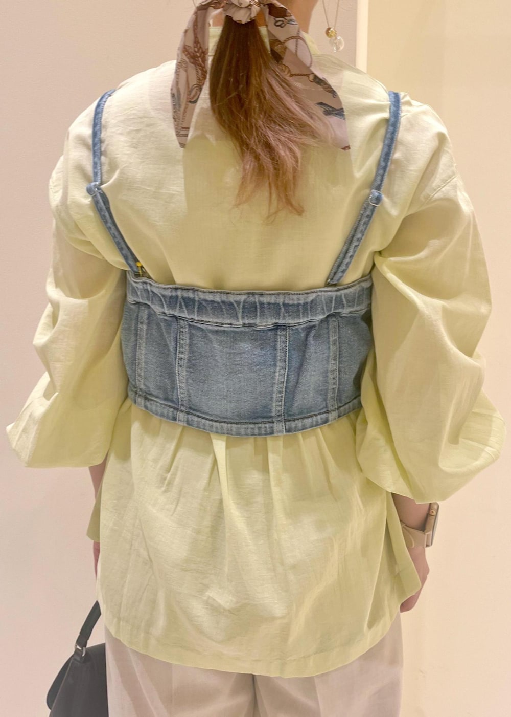 ブラック系のハンドバッグ、ブルー系のベスト、イエロー系のシャツ/ブラウスを着用したレディースの春コーディネートの7枚目の写真