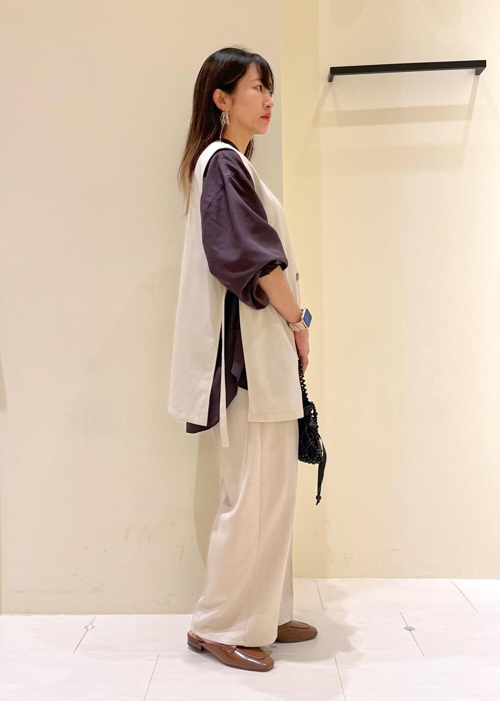 イエロー系のローファー、ブラック系のハンドバッグ、ベージュ系のベストを着用したレディースの春コーディネートの4枚目の写真