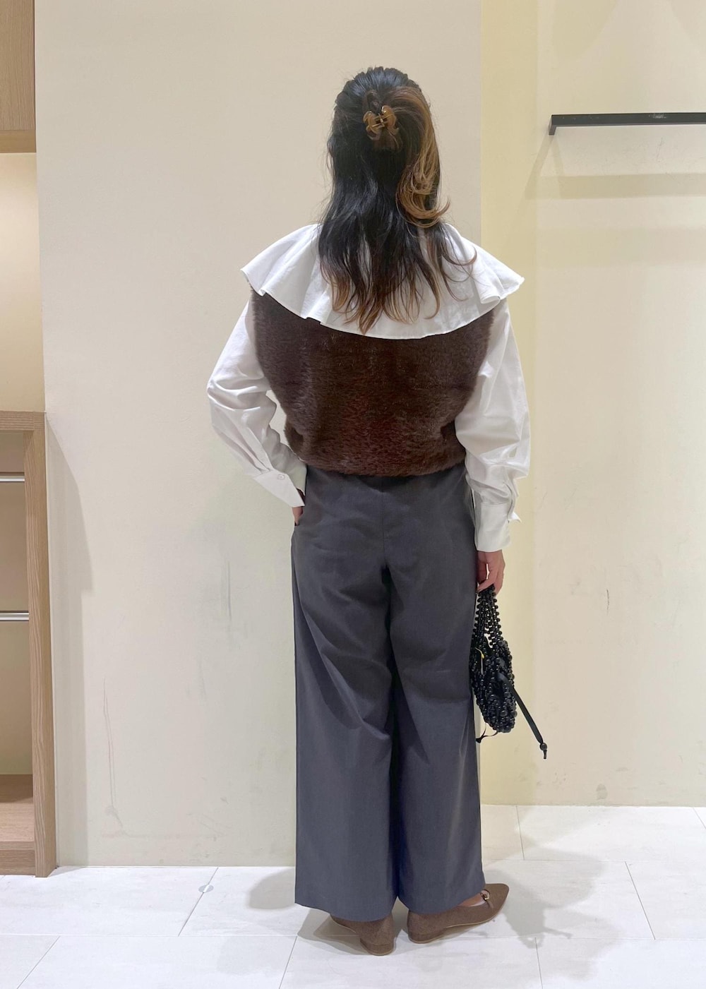 ホワイト系のシャツ/ブラウス、ブラック系のハンドバッグ、ブラウン系のベストを着用したレディースの秋コーディネートの4枚目の写真