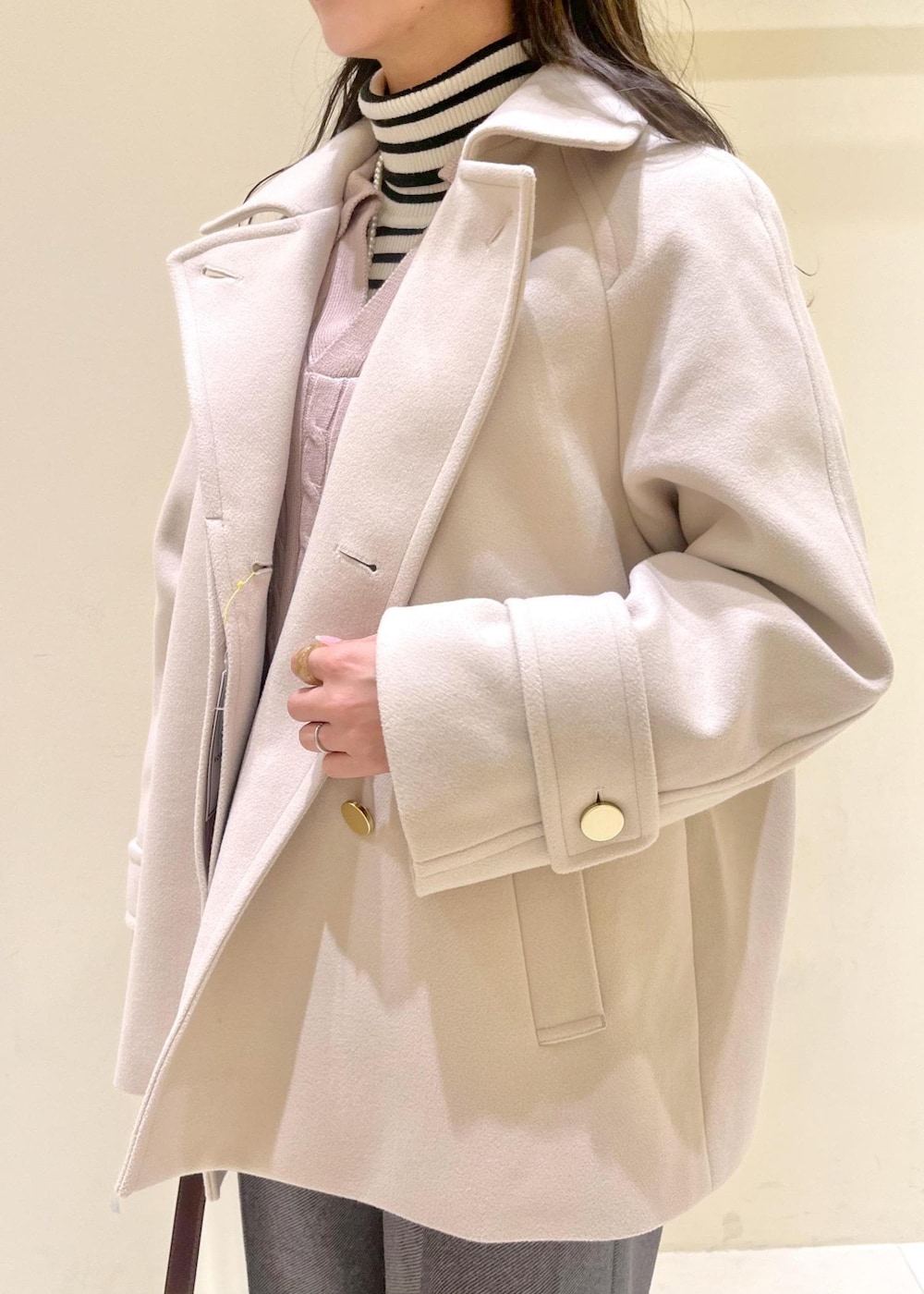 レッド系のショルダーバッグ、ホワイト系のニット/セーター、ベージュ系のその他アウターを着用したレディースの冬コーディネートの4枚目の写真