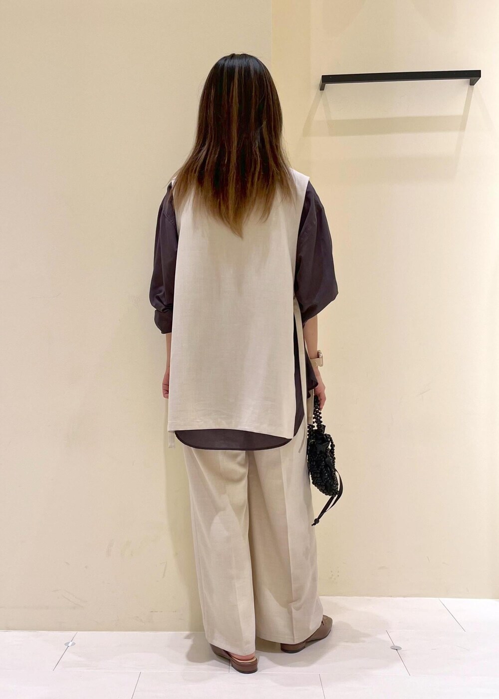 イエロー系のローファー、ブラック系のハンドバッグ、ベージュ系のベストを着用したレディースの春コーディネートの5枚目の写真