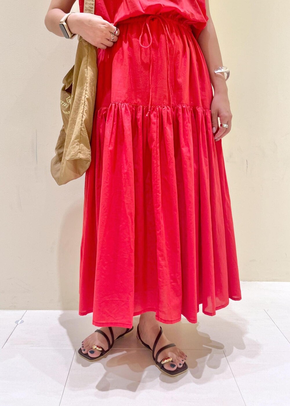 ブラウン系のサンダル、レッド系のワンピース、ブラウン系のトートバッグを着用したレディースの夏コーディネートの8枚目の写真