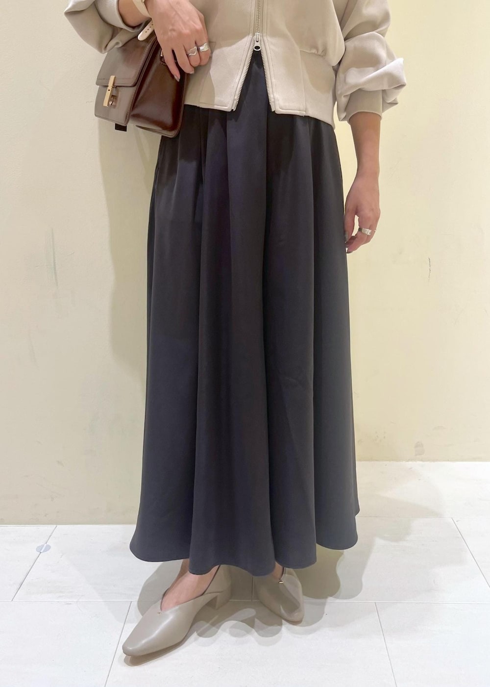 レッド系のショルダーバッグ、ベージュ系のパンプス、ベージュ系のカーディガン/ボレロを着用したレディースの秋コーディネートの8枚目の写真