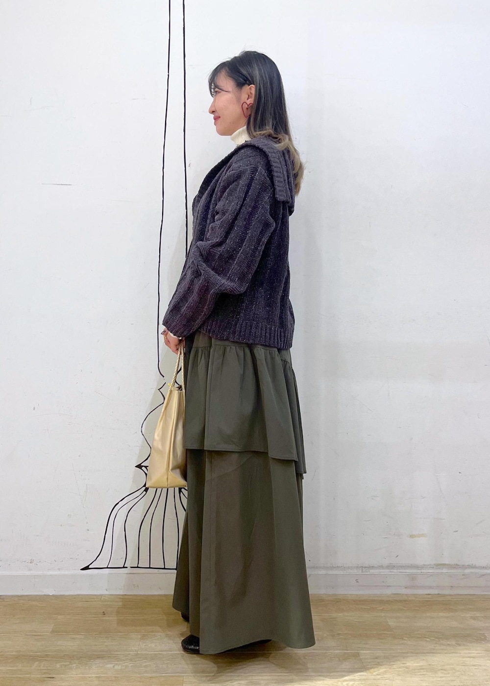 ホワイト系のニット/セーター、ブラック系のバレエシューズ、グリーン系のスカートを着用したレディースの冬コーディネートの3枚目の写真