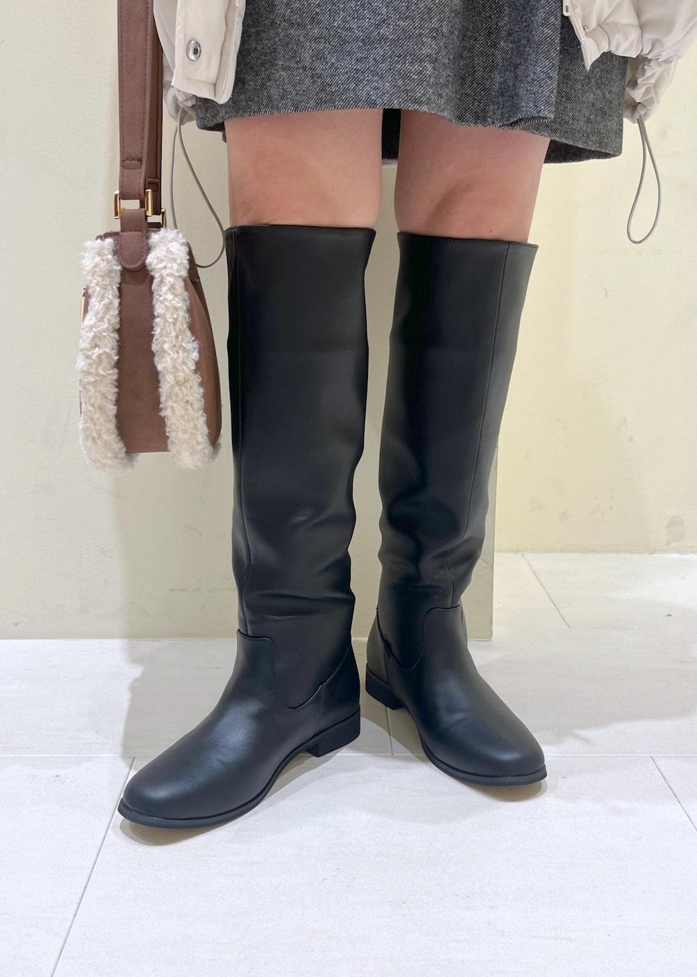 ブラック系のブーツ、ブラウン系のショルダーバッグ、ブルー系のニット/セーターを着用したレディースの冬コーディネートの9枚目の写真