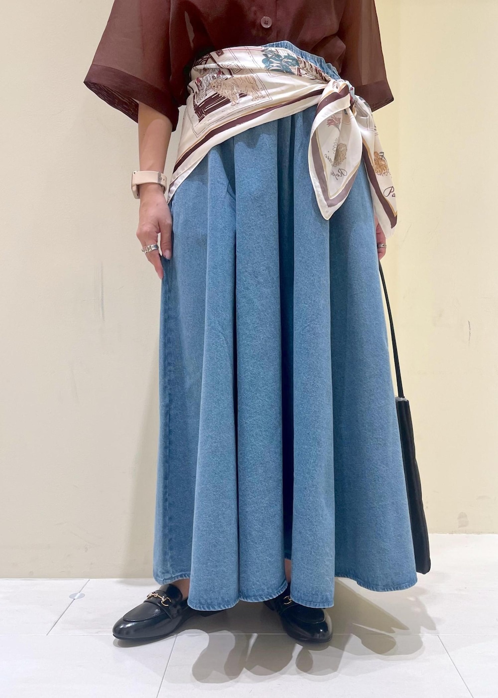 ブラック系のトートバッグ、ブラウン系のシャツ/ブラウス、ブルー系のスカートを着用したレディースの秋コーディネートの7枚目の写真