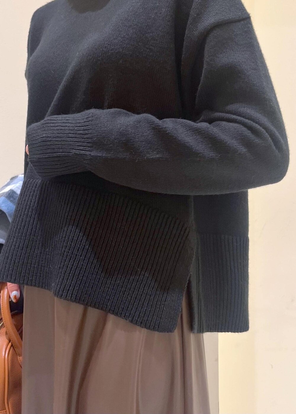 ブラウン系のスカート、ブラウン系のボストンバッグ、ブラック系のニット/セーターを着用したレディースの秋コーディネートの6枚目の写真