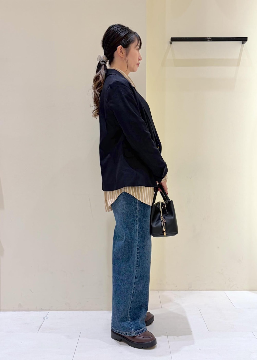 ブルー系のデニムパンツ、ブラウン系のローファー、ブラック系のトートバッグを着用したレディースの秋コーディネートの2枚目の写真