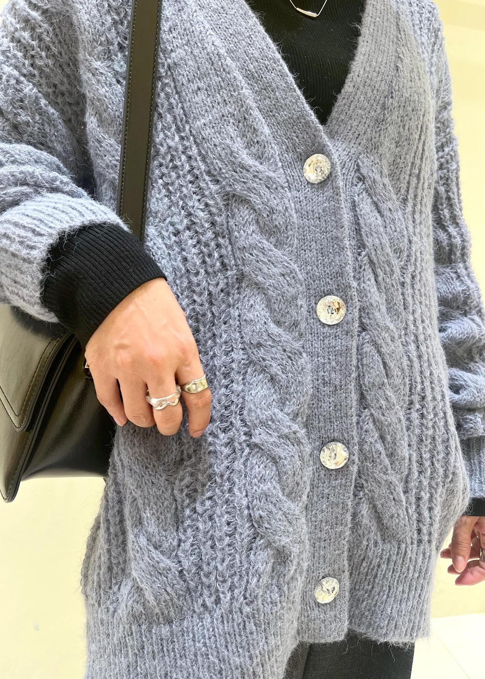 ブラック系のショルダーバッグ、ブラック系のニット/セーター、グレー系のスラックスを着用したレディースの秋コーディネートの7枚目の写真