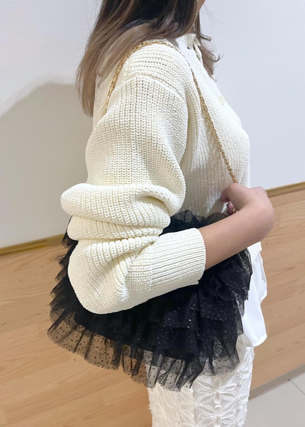 レッド系のバレエシューズ、ブラック系のショルダーバッグ、ホワイト系のスカートを着用したレディースの冬コーディネートの6枚目の写真