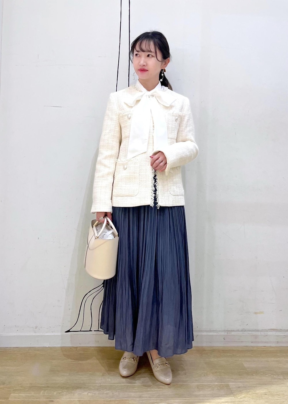 ホワイト系のショルダーバッグ、ブルー系のスカート、ベージュ系のローファーを着用したレディースの冬コーディネートの2枚目の写真