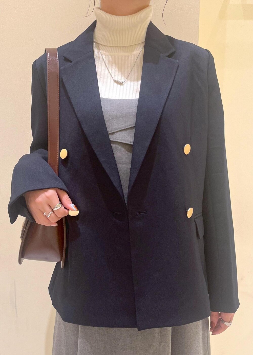 レッド系のショルダーバッグ、ホワイト系のニット/セーター、グレー系のワンピースを着用したレディースの秋コーディネートの5枚目の写真