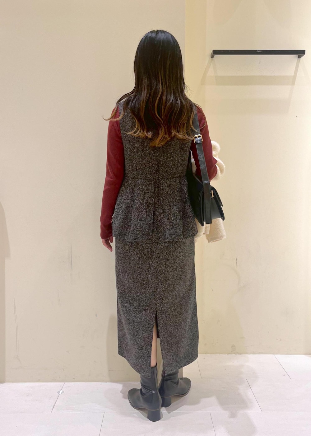 グレー系のジャンパースカート、ホワイト系のカーディガン/ボレロ、レッド系のニット/セーターを着用したレディースの冬コーディネートの3枚目の写真