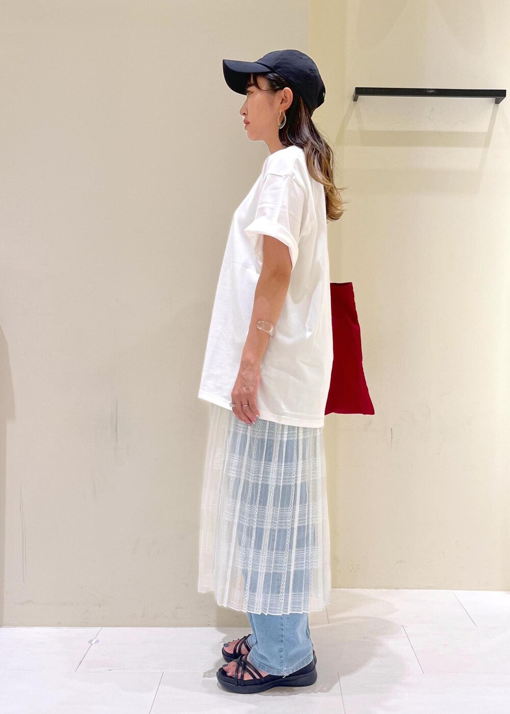 ブルー系のデニムパンツ、ホワイト系のスカート、ブラック系のサンダルを着用したレディースの夏コーディネートの3枚目の写真