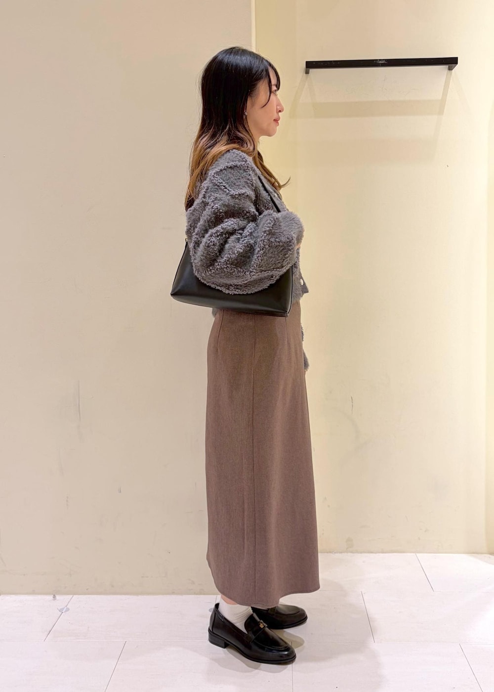 ベージュ系のスカート、グレー系のカーディガン/ボレロ、ホワイト系のTシャツ/カットソーを着用したレディースの冬コーディネートの2枚目の写真