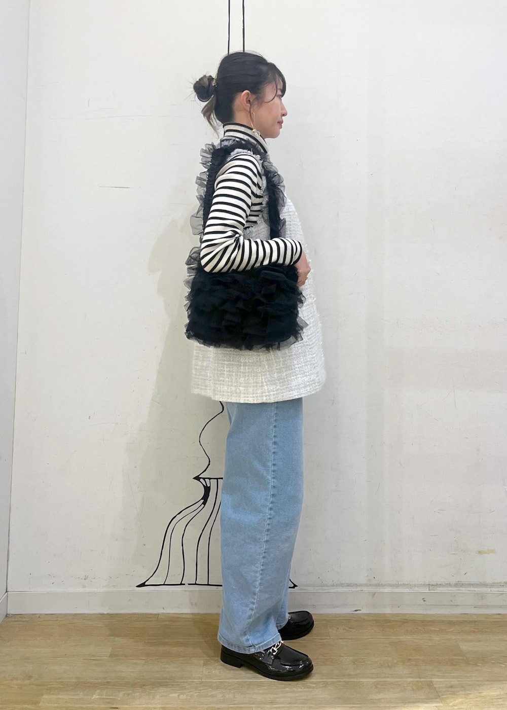 ホワイト系のニット/セーター、ブルー系のデニムパンツ、ブラック系のレインシューズを着用したレディースの冬コーディネートの4枚目の写真