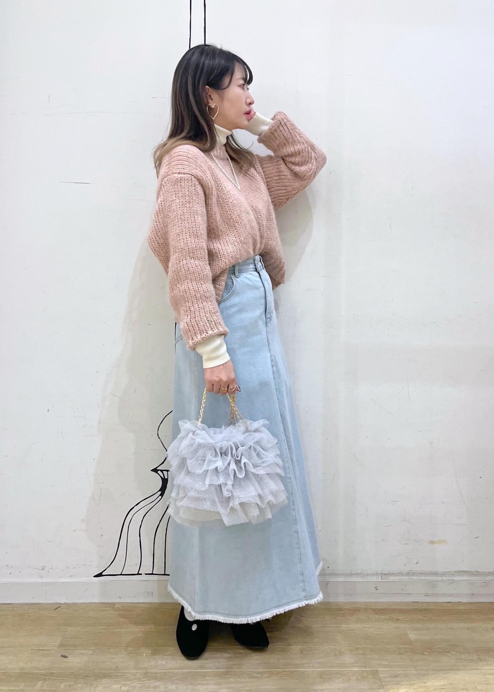 ホワイト系のニット/セーター、ブラック系のパンプス、ブルー系のデニムスカートを着用したレディースの冬コーディネートの3枚目の写真