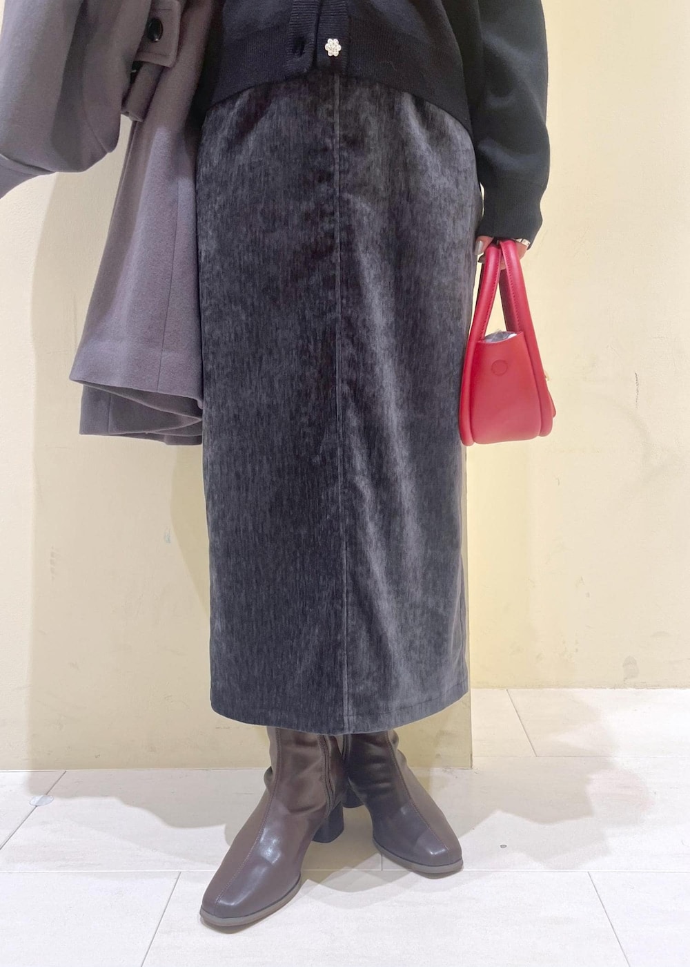 グレー系のスカート、ブラック系のカーディガン/ボレロ、ホワイト系のニット/セーターを着用したレディースの冬コーディネートの6枚目の写真