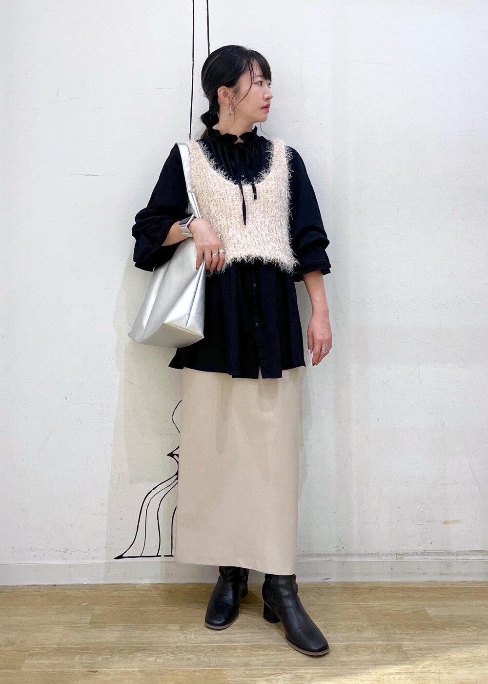 ベージュ系のスカート、ベージュ系のベスト、ブラック系のシャツ/ブラウスを着用したレディースの秋コーディネートの2枚目の写真