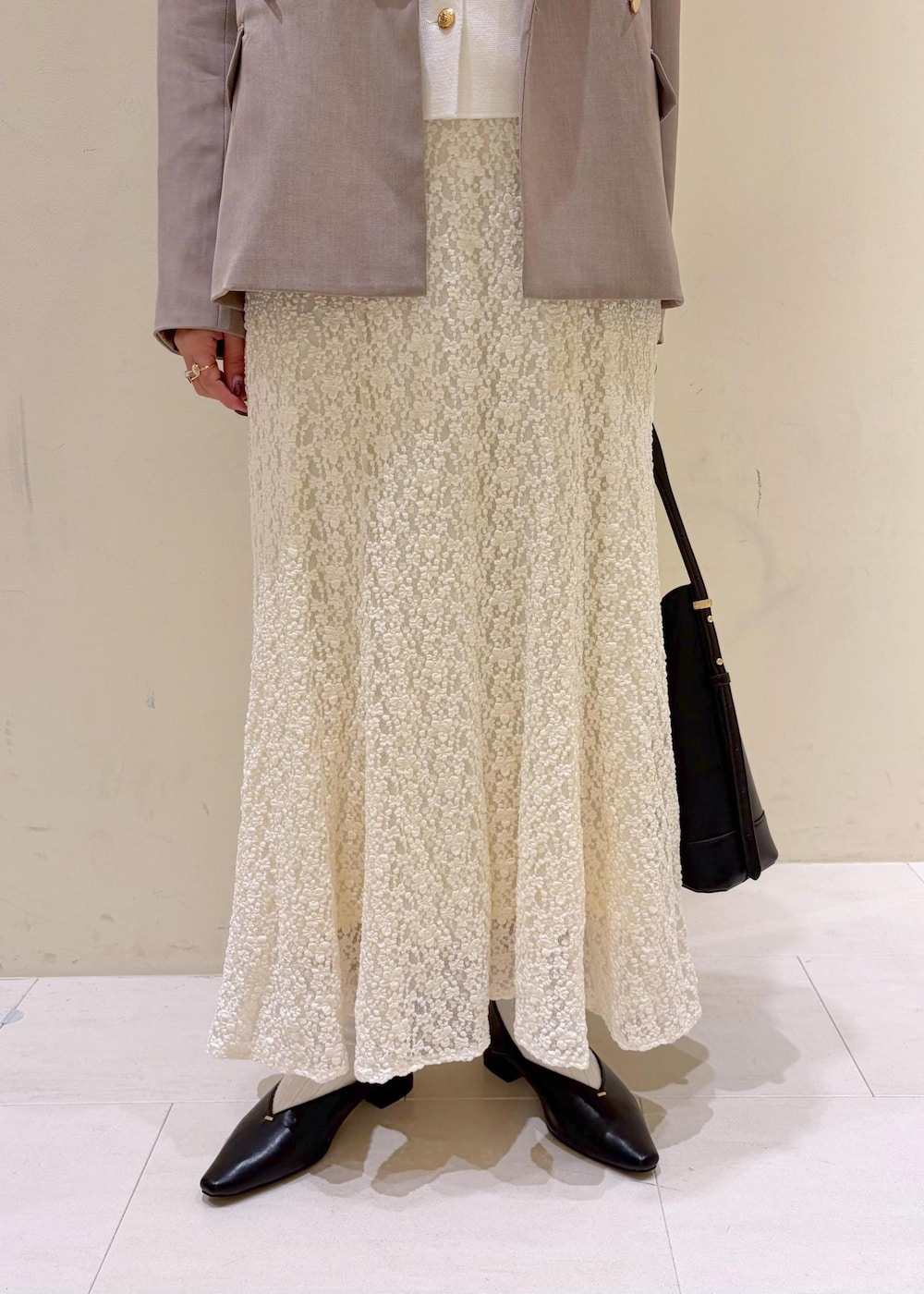 ブラック系のショルダーバッグ、ホワイト系のスカート、ホワイト系のカーディガン/ボレロを着用したレディースの冬コーディネートの6枚目の写真