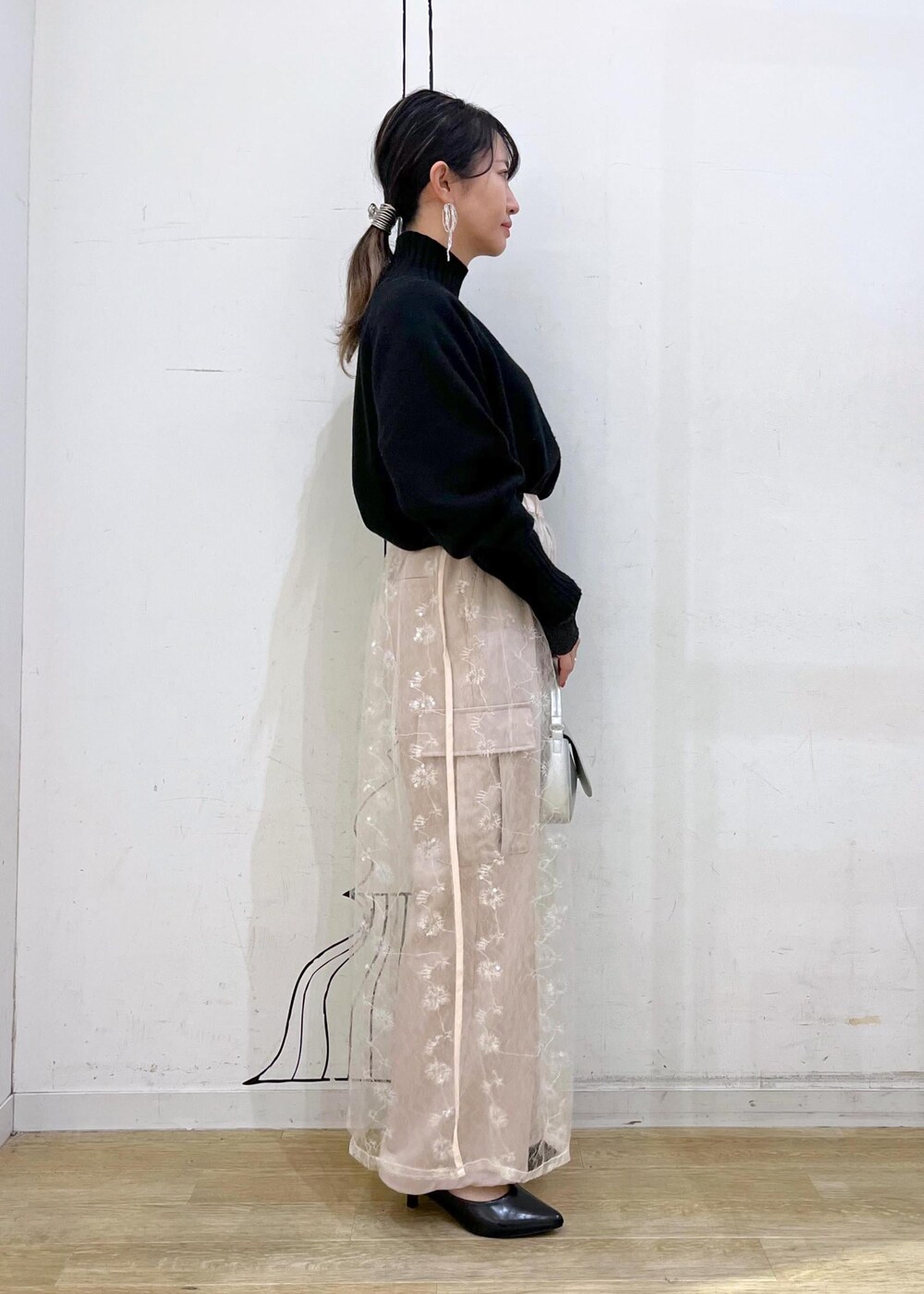 ブラック系のニット/セーター、ホワイト系のスカート、ブラック系のパンプスを着用したレディースの冬コーディネートの3枚目の写真