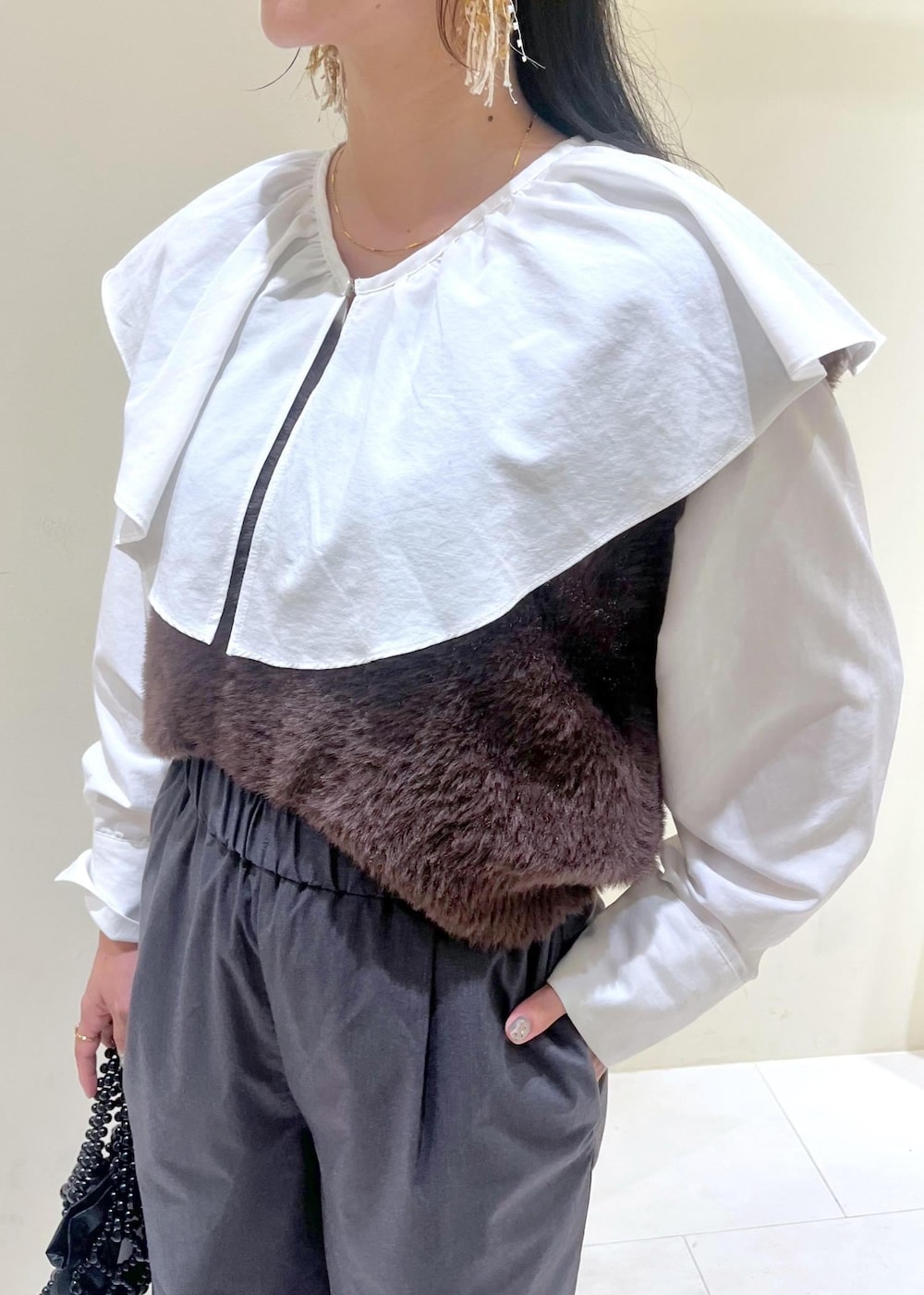 ホワイト系のシャツ/ブラウス、ブラック系のハンドバッグ、ブラウン系のベストを着用したレディースの秋コーディネートの5枚目の写真