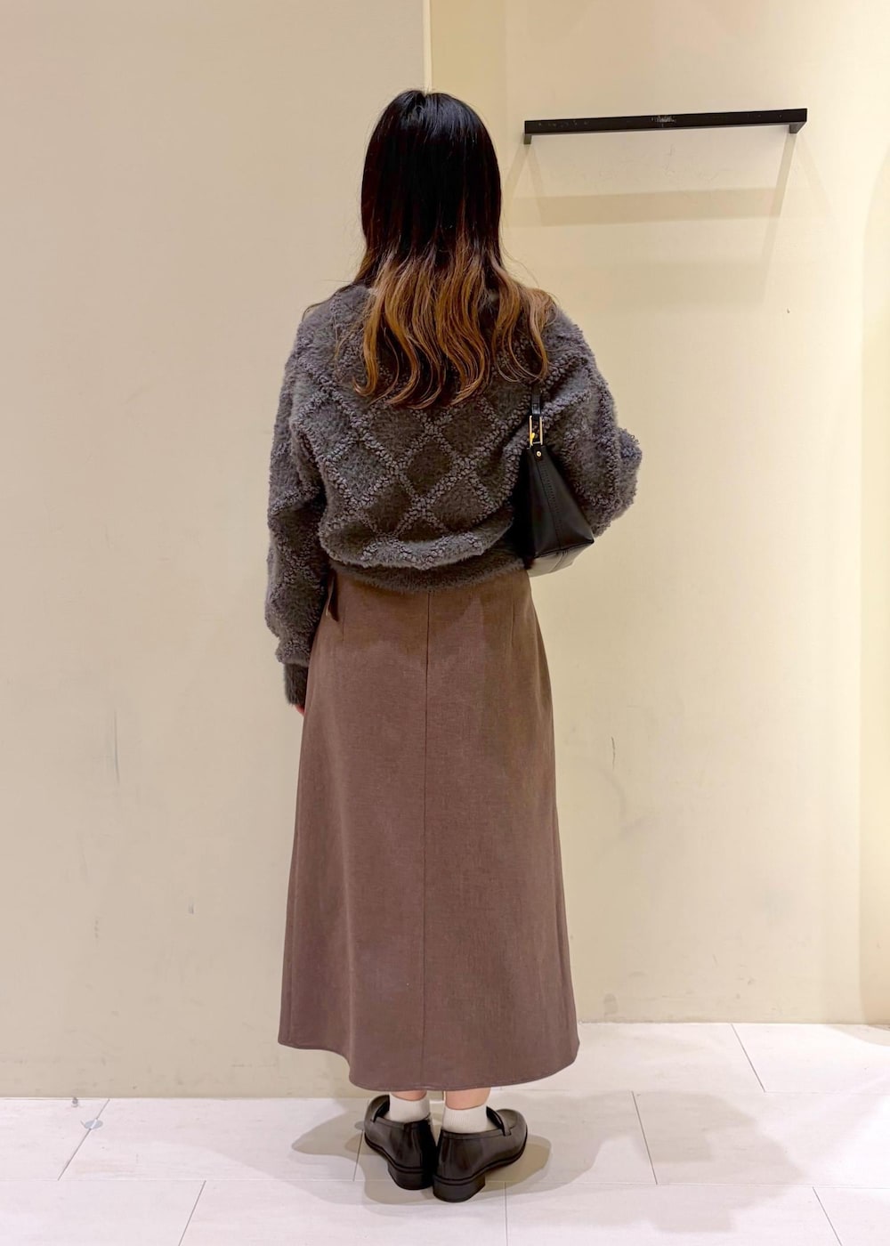 ベージュ系のスカート、グレー系のカーディガン/ボレロ、ホワイト系のTシャツ/カットソーを着用したレディースの冬コーディネートの3枚目の写真