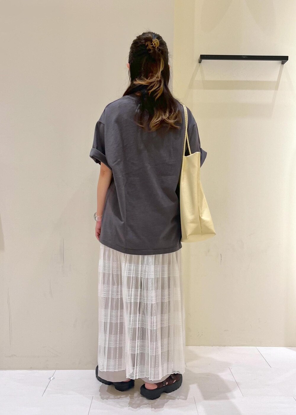 イエロー系のトートバッグ、ホワイト系のスカート、ベージュ系のその他パンツを着用したレディースの夏コーディネートの4枚目の写真