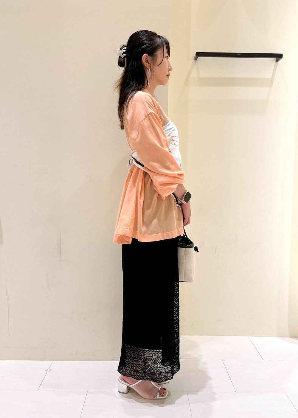 オレンジ系のシャツ/ブラウス、シルバー系のパンプス、ブラック系のトートバッグを着用したレディースの夏コーディネートの3枚目の写真