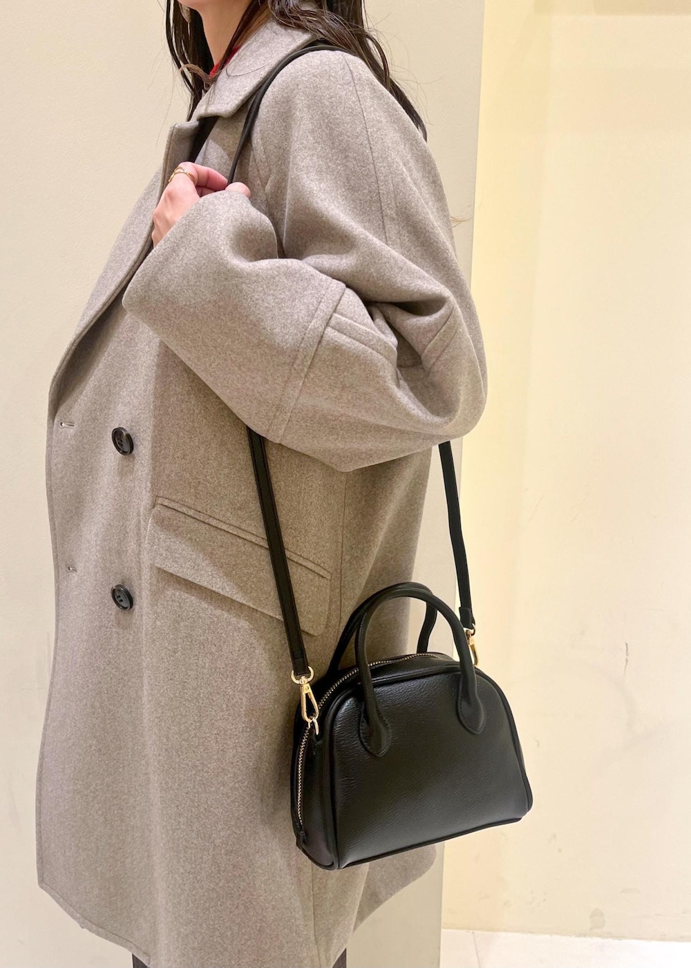 ブラック系のショルダーバッグ、レッド系のニット/セーター、ブラウン系のピーコートを着用したレディースの冬コーディネートの9枚目の写真