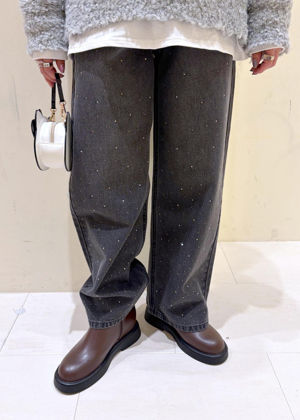 ブラック系のデニムパンツ、ブラウン系のブーツ、グレー系のニット/セーターを着用したレディースの冬コーディネートの7枚目の写真