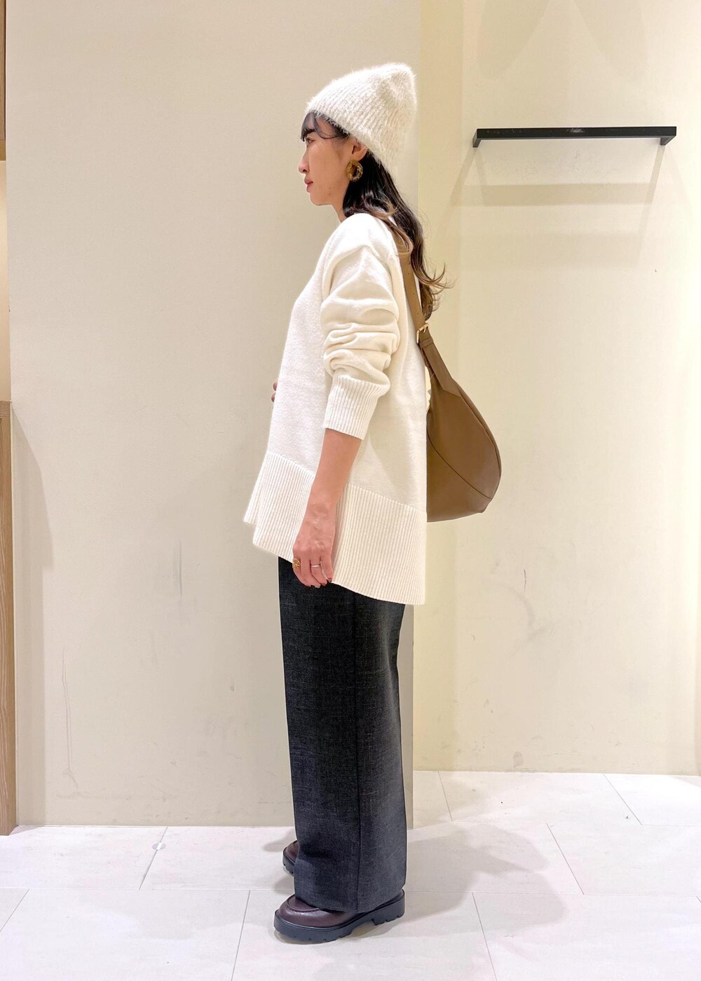 ホワイト系のニット/セーター、グレー系のスラックス、ブラウン系のローファーを着用したレディースの冬コーディネートの4枚目の写真