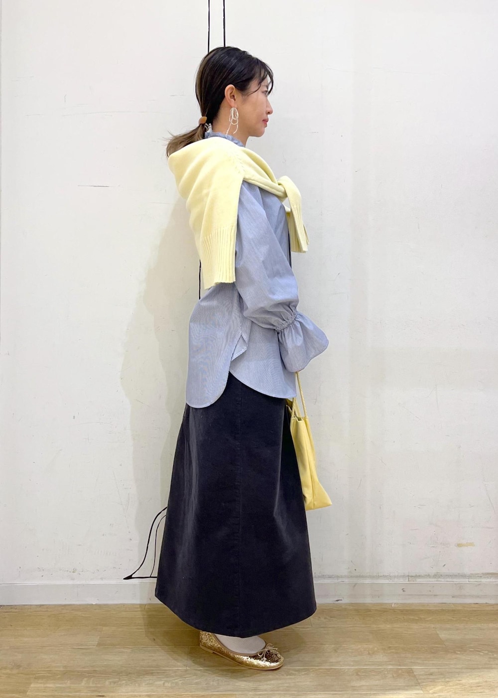 イエロー系のトートバッグ、グレー系のスカート、ブルー系のシャツ/ブラウスを着用したレディースの冬コーディネートの2枚目の写真