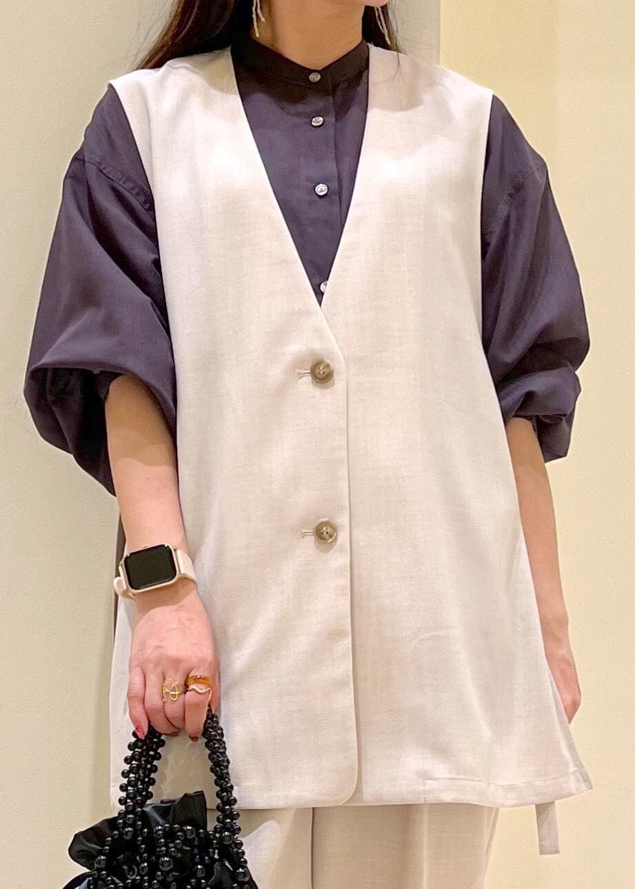 イエロー系のローファー、ブラック系のハンドバッグ、ベージュ系のベストを着用したレディースの春コーディネートの7枚目の写真