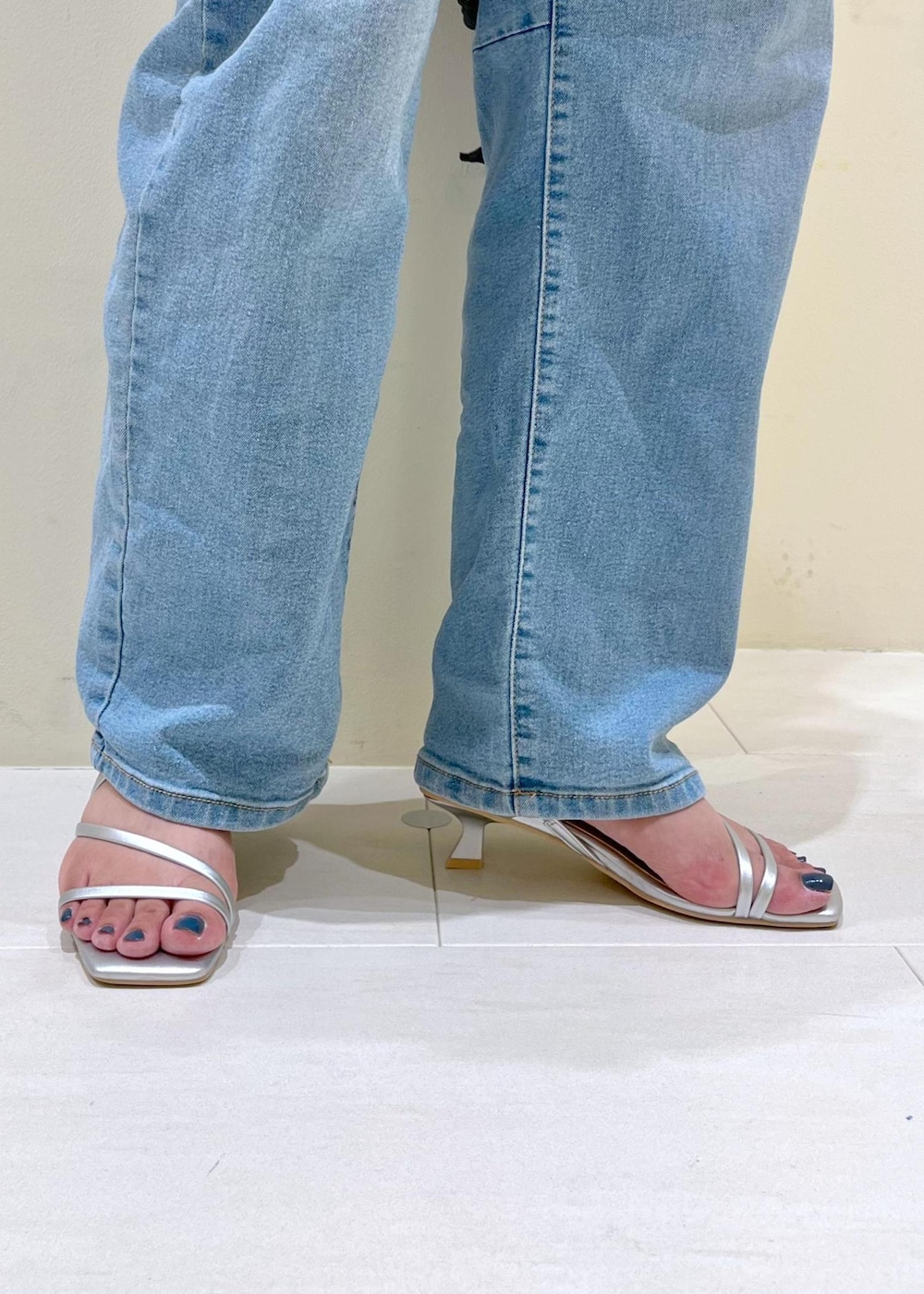 ブルー系のデニムパンツ、ブラック系のハンドバッグ、シルバー系のサンダルを着用したレディースの夏コーディネートの10枚目の写真