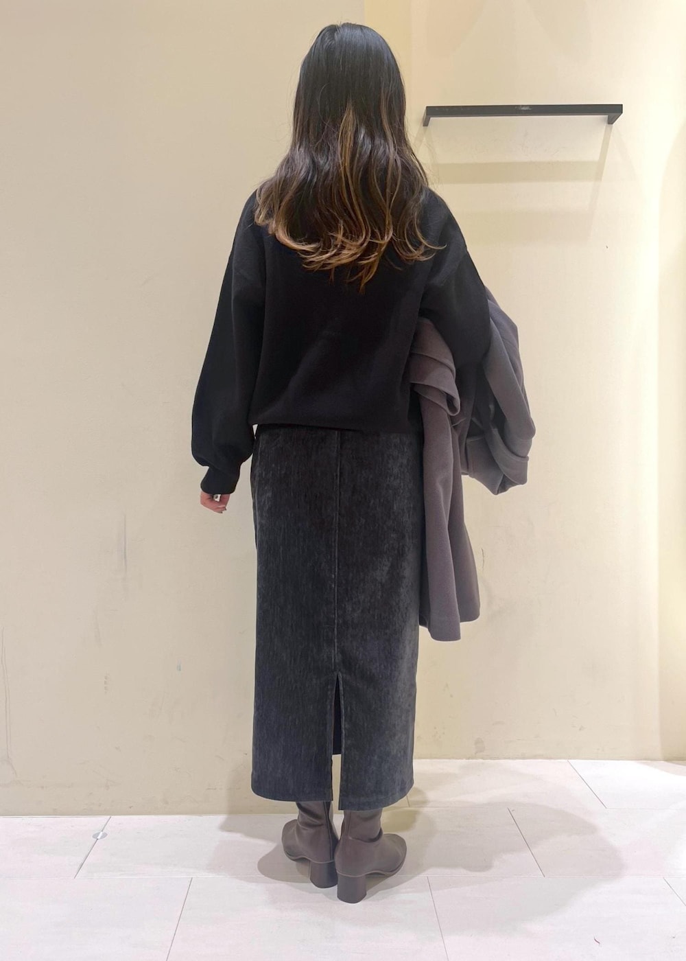 グレー系のスカート、ブラック系のカーディガン/ボレロ、ホワイト系のニット/セーターを着用したレディースの冬コーディネートの3枚目の写真