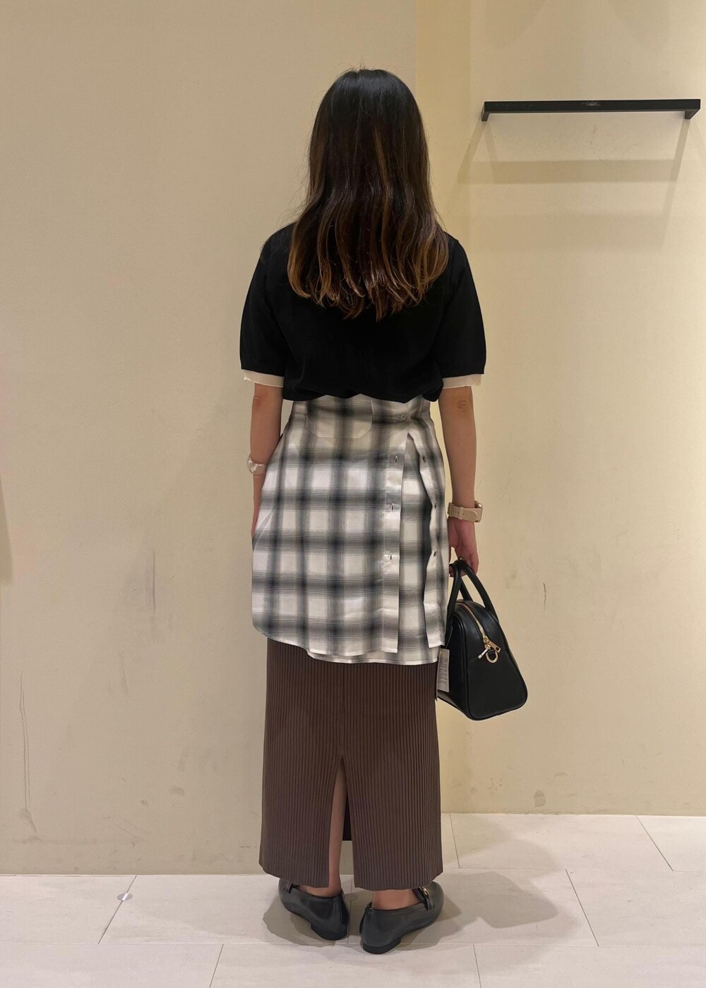 ブラック系のスカート、ブラック系のボストンバッグ、ブラック系のポロシャツを着用したレディースの夏コーディネートの4枚目の写真