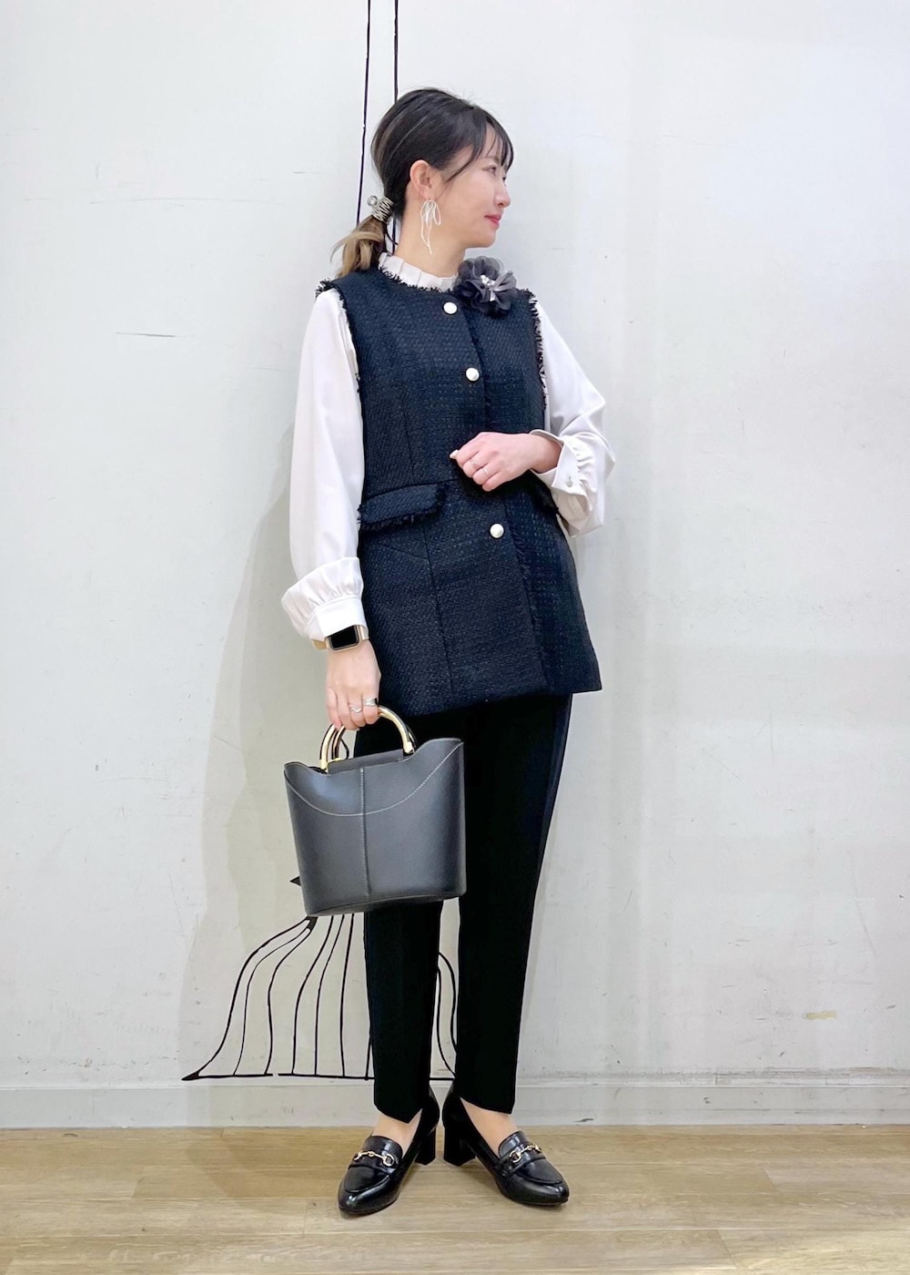 ブラック系のローファー、ブラック系のショルダーバッグ、ブルー系のベストを着用したレディースの冬コーディネートの2枚目の写真