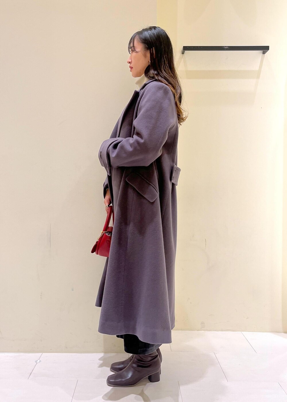 ホワイト系のニット/セーター、グレー系のチェスターコート、レッド系のショルダーバッグを着用したレディースの冬コーディネートの5枚目の写真