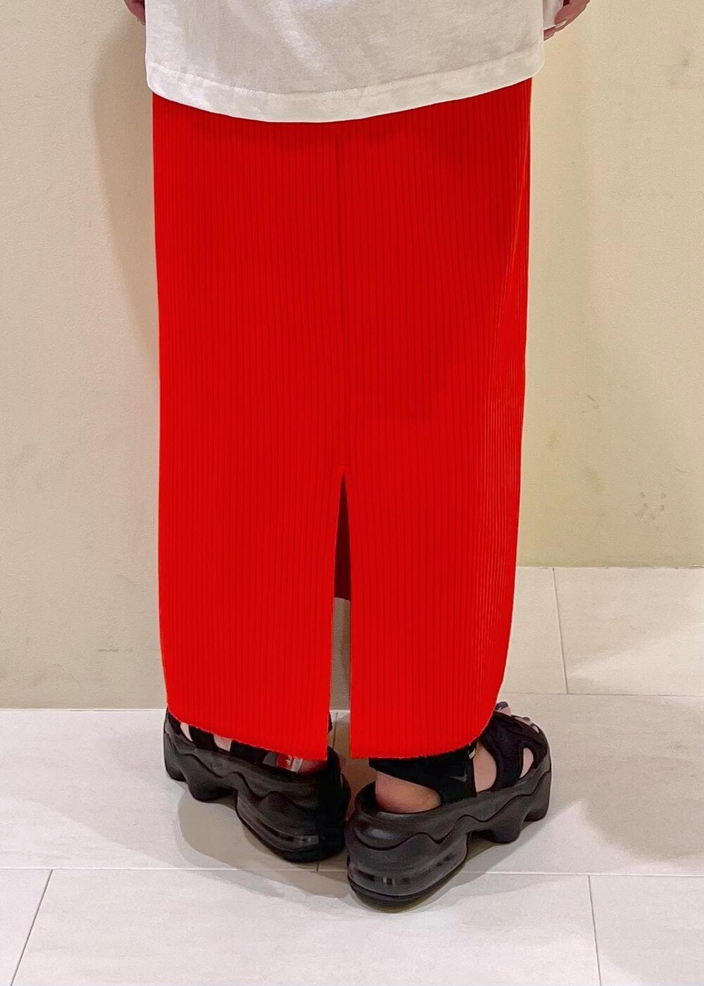 オレンジ系のスカート、ベージュ系のショルダーバッグ、ホワイト系のTシャツ/カットソーを着用したレディースの夏コーディネートの9枚目の写真