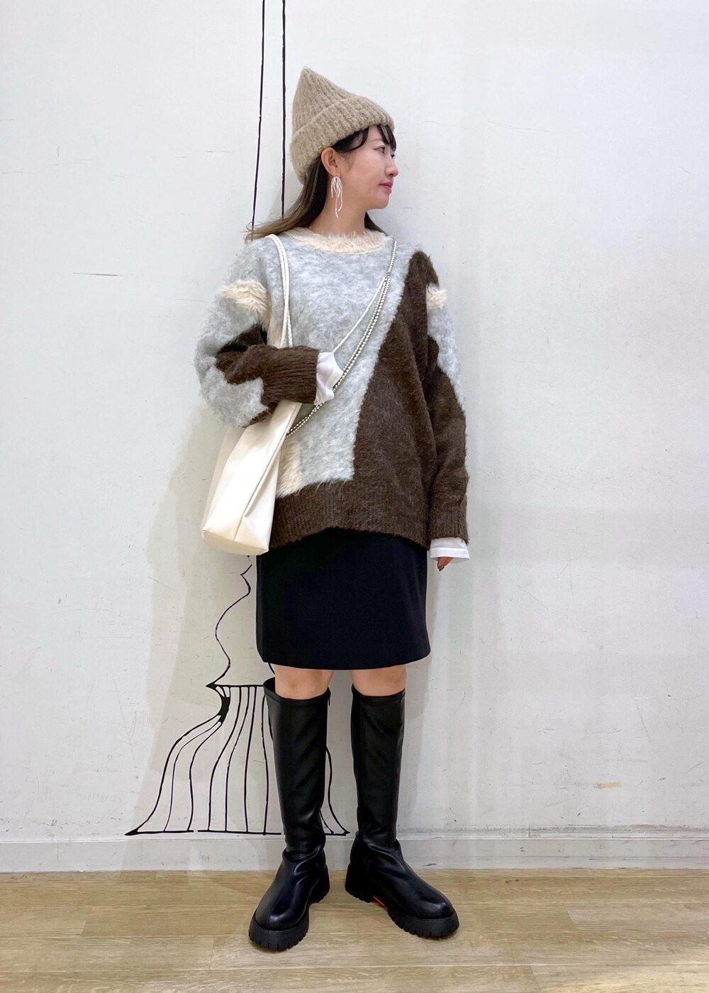 ブラック系のスカート、ブラック系のブーツ、ブラウン系のニット/セーターを着用したレディースの秋コーディネートの3枚目の写真