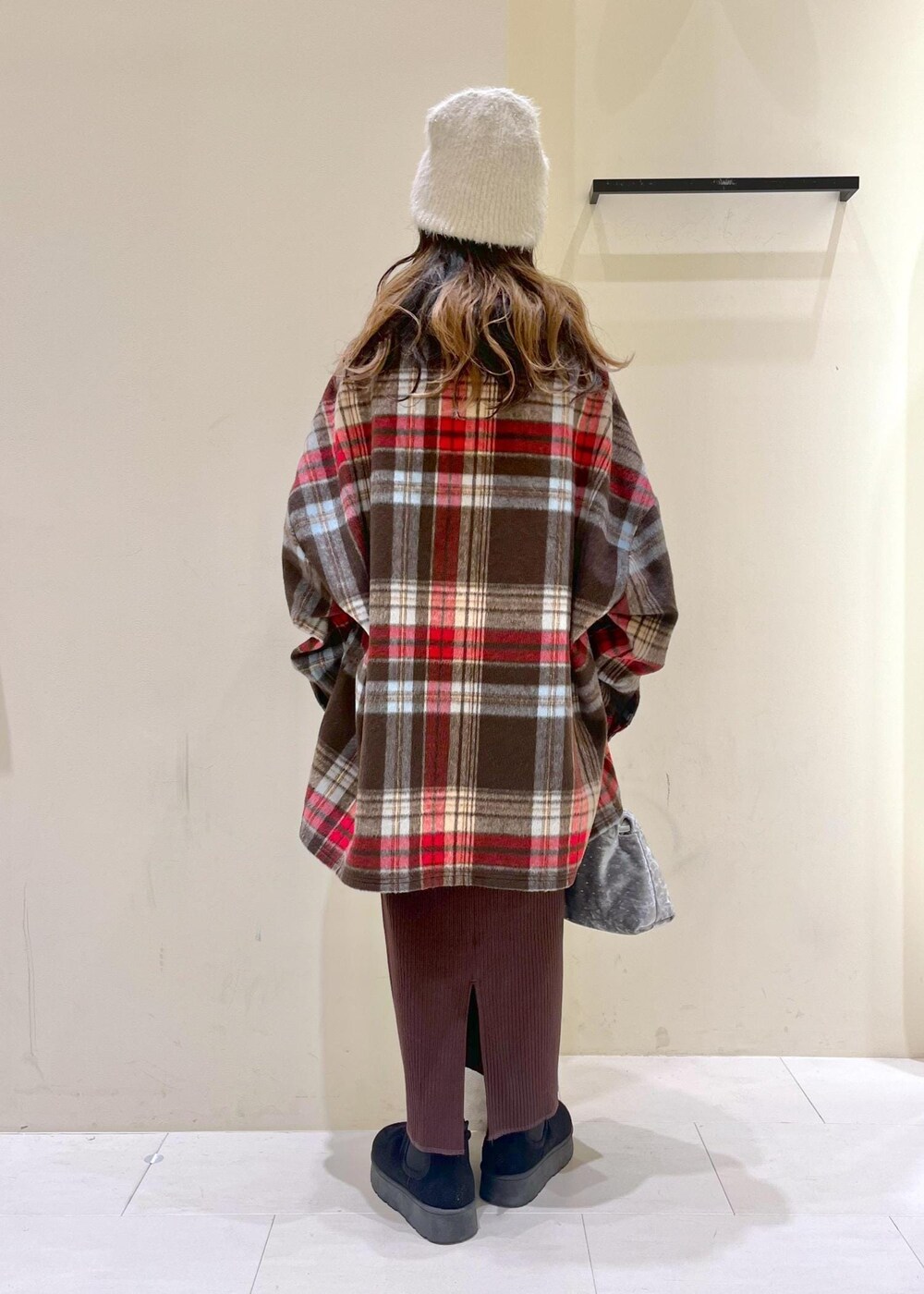 ブラック系のブーツ、ホワイト系のニット/セーター、シルバー系のハンドバッグを着用したレディースの冬コーディネートの3枚目の写真