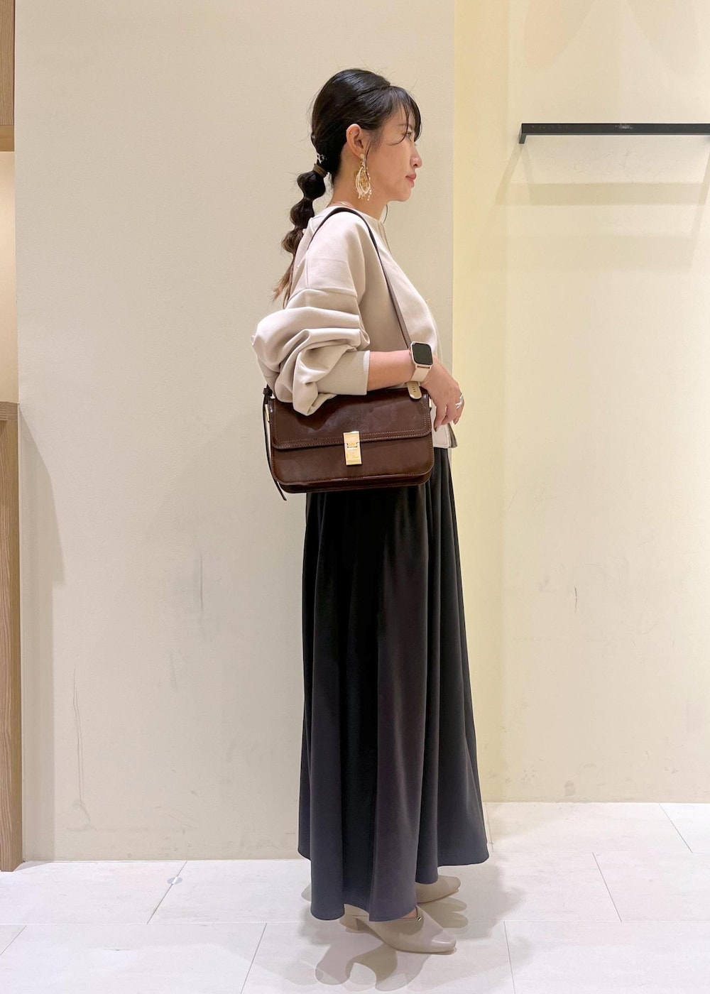 レッド系のショルダーバッグ、ベージュ系のパンプス、ベージュ系のカーディガン/ボレロを着用したレディースの秋コーディネートの3枚目の写真