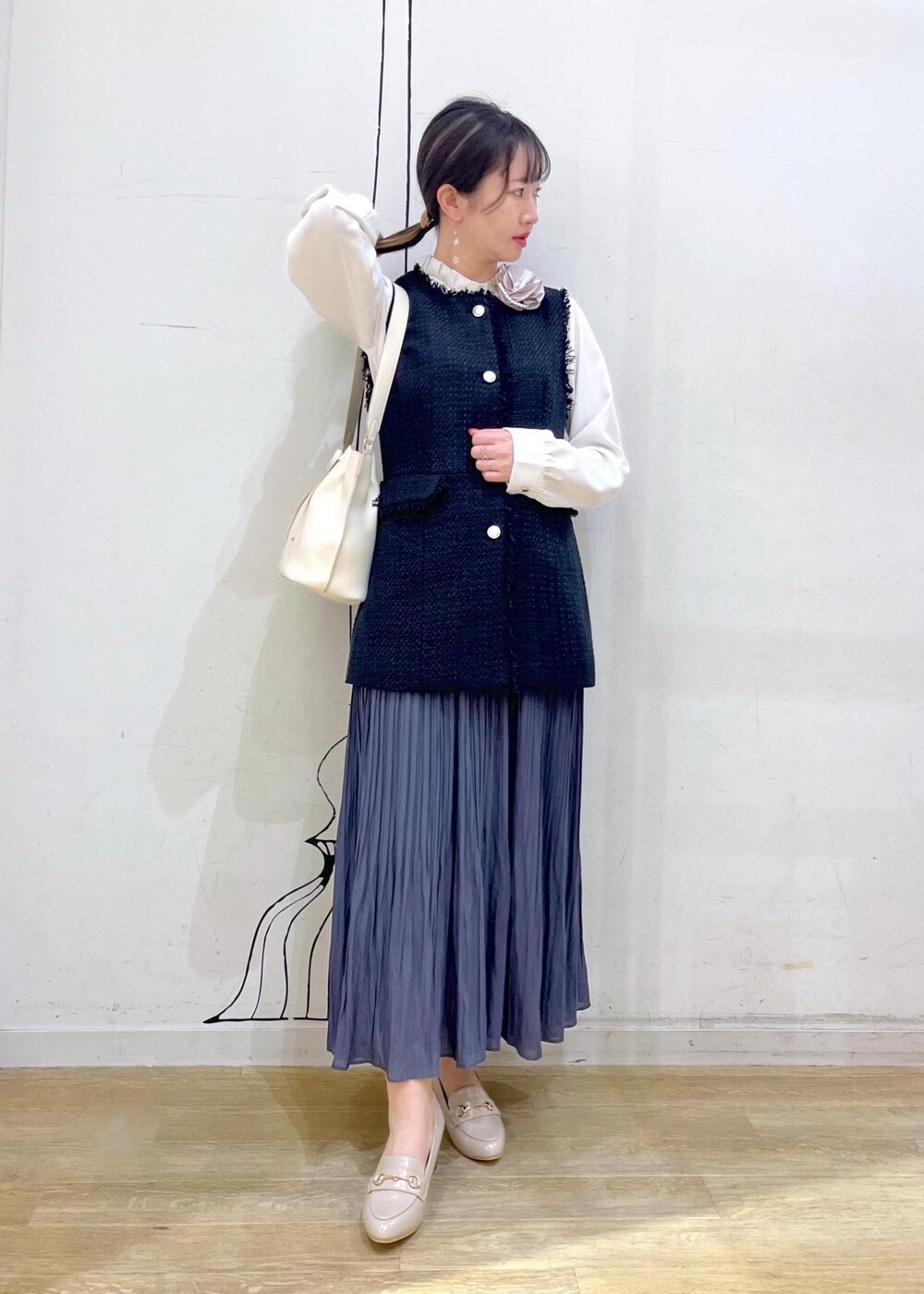 ブルー系のスカート、ベージュ系のローファー、ホワイト系のハンドバッグを着用したレディースの冬コーディネートの2枚目の写真