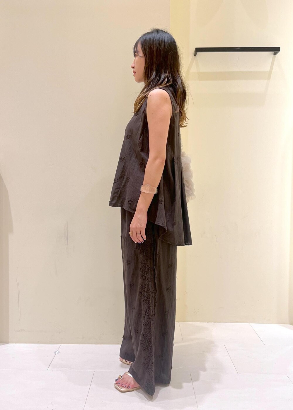 ベージュ系のショルダーバッグ、ゴールド系のサンダル、ブラック系のシャツ/ブラウスを着用したレディースの夏コーディネートの4枚目の写真