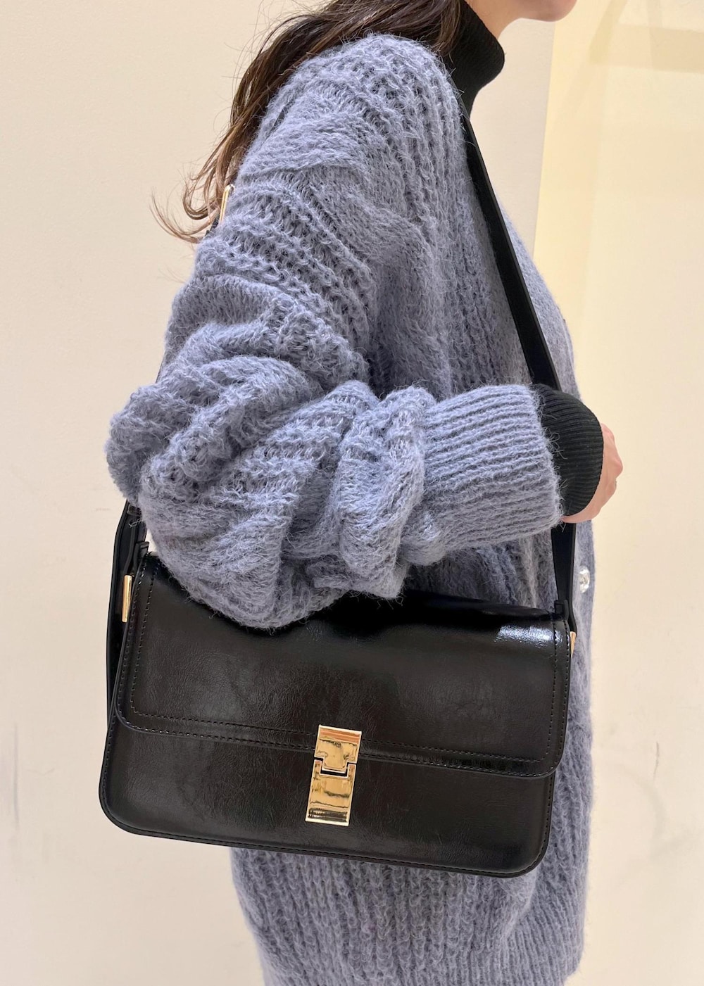 ブラック系のショルダーバッグ、ブラック系のニット/セーター、グレー系のスラックスを着用したレディースの秋コーディネートの8枚目の写真