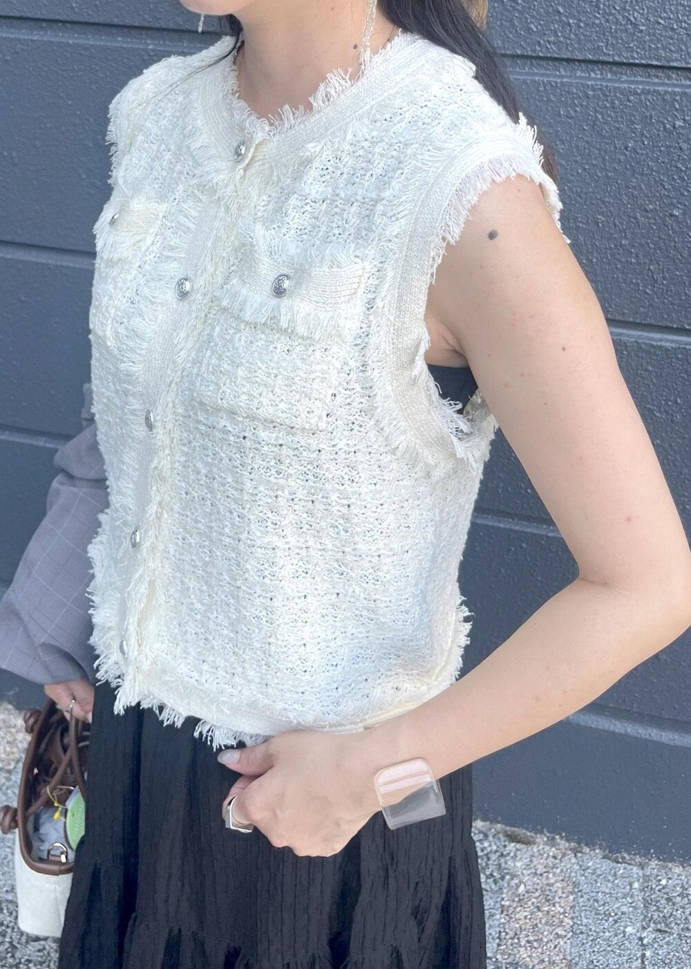 グレー系のテーラードジャケット、ブラウン系のトートバッグ、ブラック系のスカートを着用したレディースの夏コーディネートの5枚目の写真