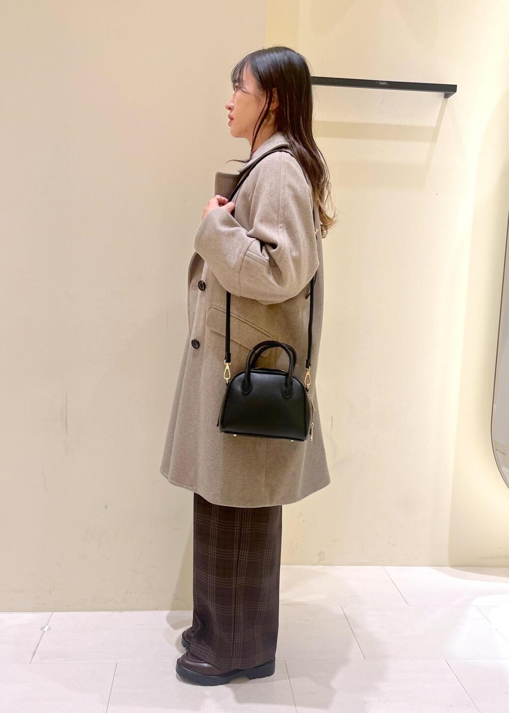 ブラック系のショルダーバッグ、レッド系のニット/セーター、ブラウン系のピーコートを着用したレディースの秋コーディネートの4枚目の写真