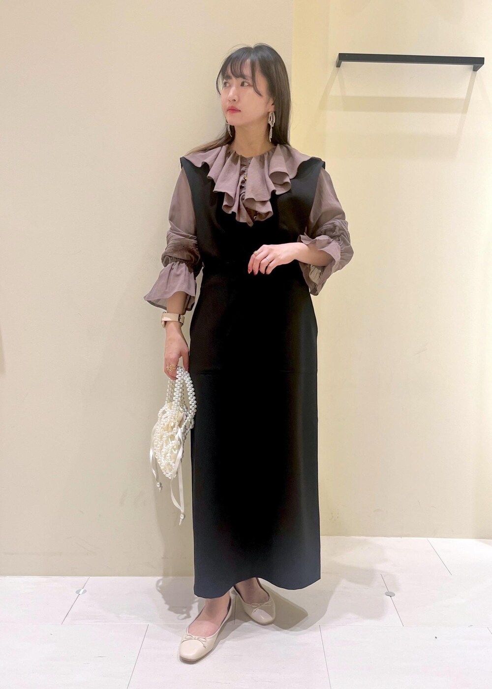 ホワイト系のバレエシューズ、ブラウン系のシャツ/ブラウス、ブラック系のジャンパースカートを着用したレディースの春コーディネートの3枚目の写真