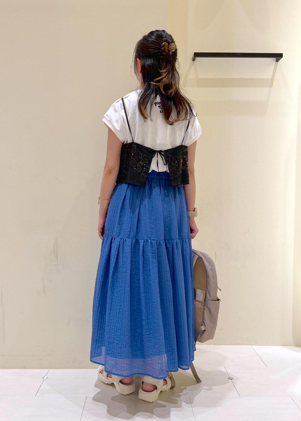 ブラック系のTシャツ/カットソー、ホワイト系のサンダル、ベージュ系のバックパック/リュックを着用したレディースの夏コーディネートの3枚目の写真